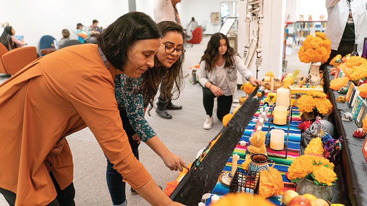 a faculty member and a student look over the ofrenda display